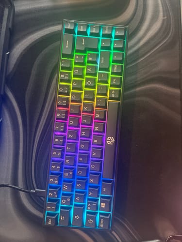 Kunde zeigt das RZ Mousepad Liquid Black auf einem Schreibtisch mit einer leuchtenden Tastatur darauf.