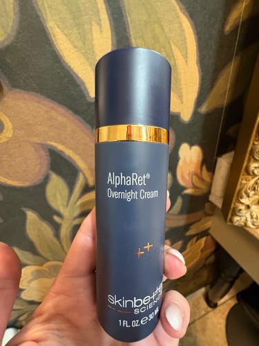 Reviewer's hand holding the sleek, blue bottle of AlphaRet Overnight Cream.