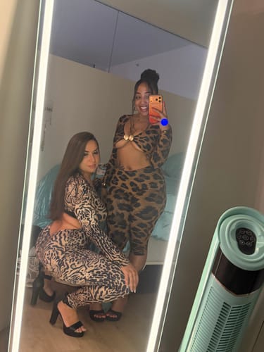 Reviewer in a mirror selfie showing a full view of the animal print Naked Print Cutout Capri Jumpsuit with another person.