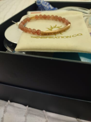 Customer's 'I AM WITH YOU ALWAYS' bracelet with reddish beads shown resting on its pouch inside the packaging.