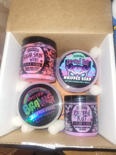 Reviewer's Sugar Spun Webs Sugar Scrub shown in an open box with three other bath products.