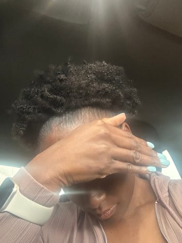 Reviewer with defined, curly hair in a high puff after using the VIRAL Healthy Hair Bundle.