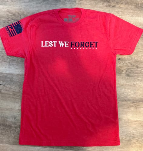 Customer's red t-shirt laid flat, showing the front text 'LEST WE FORGET' and sleeve flag patch.
