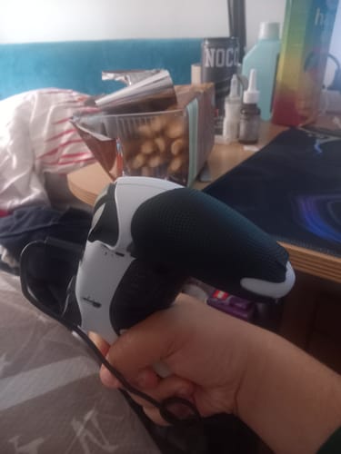 Ein Rezensent hält einen PS5-Controller mit den RZ Controller Grips in der Hand.
