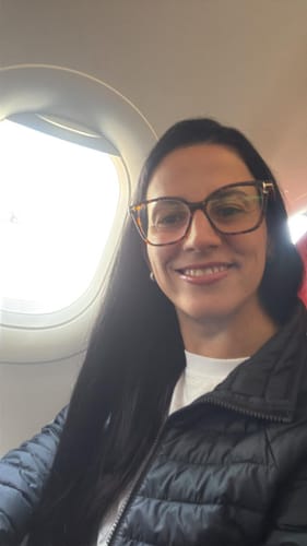 Cliente sorrindo e usando a armação de grau Leopardo dos Óculos Barcelona dentro de um avião.