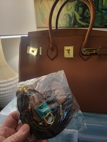 Customer's brown Warkin Bag with gold hardware, showing the new shoulder strap still in its plastic packaging.