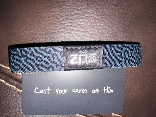 Customer's patterned 'Cast Your Cares On Him' bracelet laid over a card with the same verse written on it.