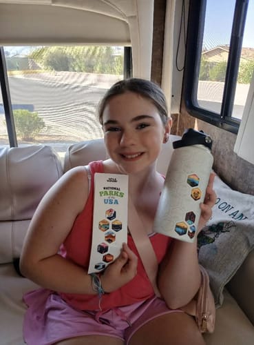 Customer holding a white World Explorer Water Bottle with several stickers and the matching sticker sheet.