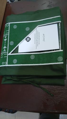 Customer's folded Green Palisade Jacquard Agbada, showing the intricate white embroidery and a thank you card.