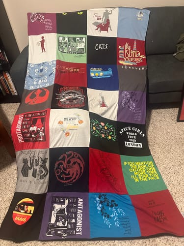 Reviewer's finished Project Repat T-Shirt Quilt, a colorful collage of memorable shirts, draped over a couch.