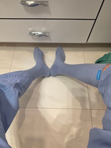 Customer wearing the light blue Spring Sky Blue socks with matching trousers on a tiled floor.
