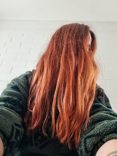 Clienta con cabello largo y cobrizo, teñido con Henna Jamila, cubriendo su rostro.