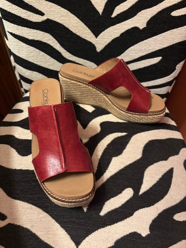Customer's red Corky's Kiss N Tell Wedges with woven platforms on a zebra-print chair.