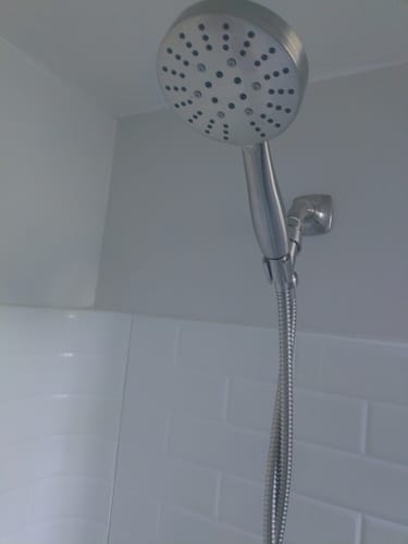 Reviewer's 3-Spray Handheld Shower Head Set installed in a white tiled shower.