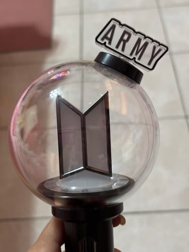 Customer's hand holds a BTS light stick with the 'ARMY' accessory part attached to the top.