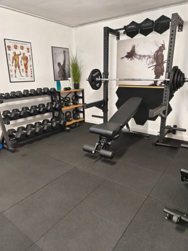 Ein Kunde zeigt das Langhantel Set Zeta Space in einem gut ausgestatteten Homegym.