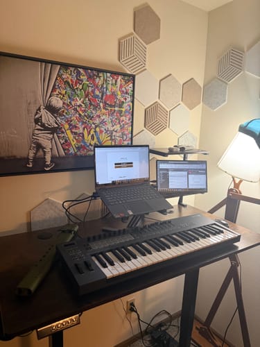 Reviewer's Model-X 2.0 Stand holding a laptop on a desk in a music studio setup.
