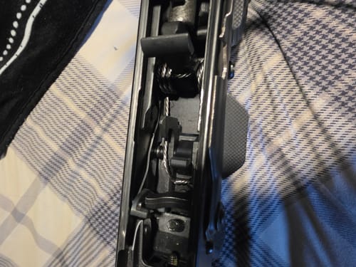 Close-up view of a customer's AK-47 FRT Super Safety installed in the trigger mechanism of a rifle.