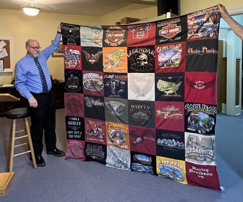 Customer holding up their large Project Repat T-Shirt Quilt made from a collection of Harley-Davidson t-shirts.