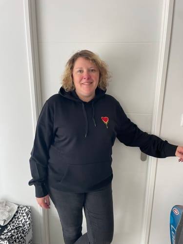 Une cliente sourit en portant le sweat à capuche noir Hoodie Coeur.