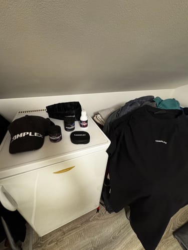 Customer's black Pill box displayed on a mini-fridge with other brand supplements and apparel.