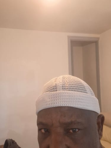 Close-up of a reviewer wearing a white mesh Brimless Docker Hat indoors.