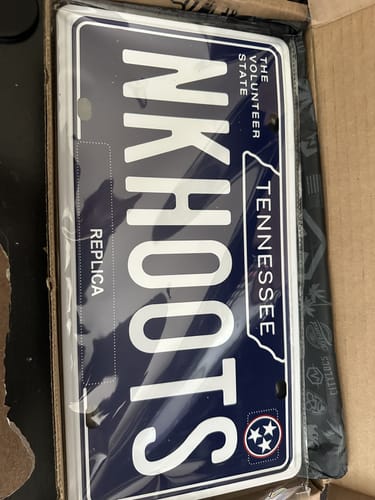 Customer's custom Tennessee metal license plate with 'NKHOOTS' text, shown inside its box.