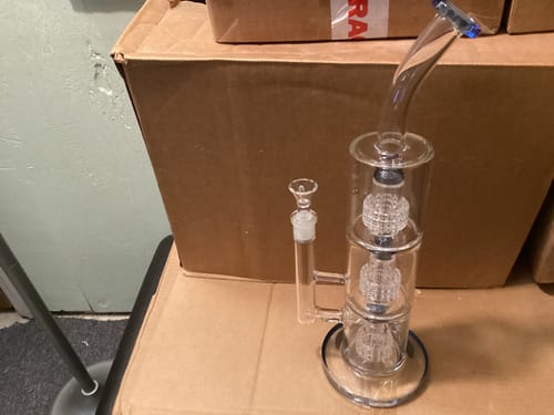 Customer's clear glass Trinity water pipe with three percolators, unboxed and standing on a cardboard box.