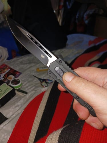 Reviewer holding the VT Striker Dual Action OTF Knife with the dark tanto blade extended.