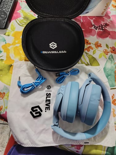 Cliente mostrando los audífonos Pulse ANC 2Gen celestes junto a su estuche de viaje y cables.