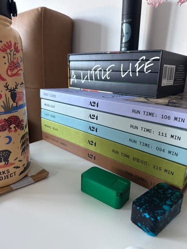 Reviewer's two metal pill cases from the bundle, one green and one speckled, on a bedside table.