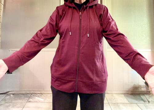 Reviewer wearing the Toasted Garnet Ryann Hoodie with arms out to show the relaxed fit and length.