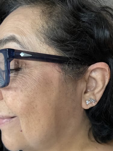 Close-up of a customer wearing the silver Coco Bow Comfort Earrings, showing their comfortable in-ear fit.