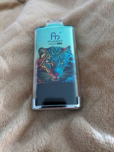 Customer's RandM Tornado 40000 vape with a colorful leopard design, lying on a soft, brown surface.