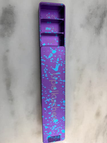 Reviewer's purple vitamin case with blue splatter, engraved 'Upelkuchen', shown partially open to reveal inner compartments.