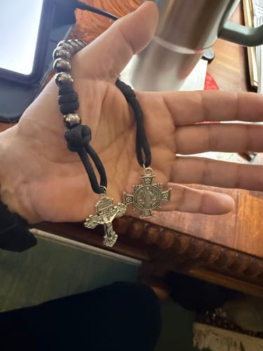 Customer holding the Dual Use Pocket Rosary, showing its silver beads, black cord, crucifix, and medal.