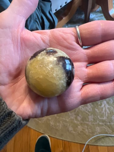 Customer holding a round, mottled Septarian crystal from the VIP Crystal Club in their palm.