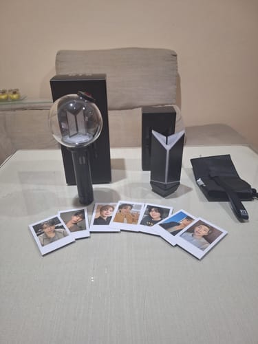 Customer's unboxed BTS Official Light Stick Ver.4, cradle, photo cards, and packaging displayed together on a flat surface.
