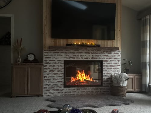 Customer's Modern Flames Orion firebox installed in a whitewashed brick surround, showing realistic flames.