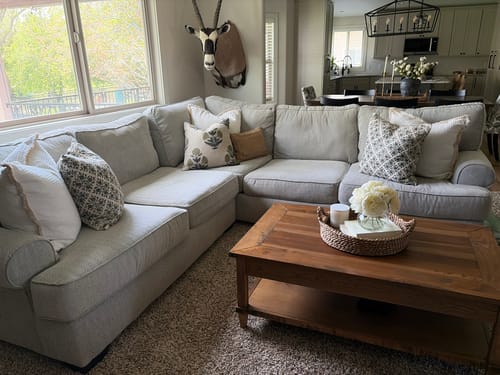 Customer's Lottie in Linen pillow covers arranged on a light grey sectional sofa in a living room.
