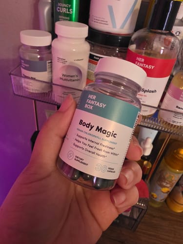 Customer holding a bottle of Body Magic Chlorophyll Pills, showing the dark capsules inside the clear container.