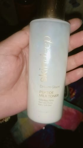 Customer holding the bottle of DREAM GLAZE Peptide Milk Toner in their hand.