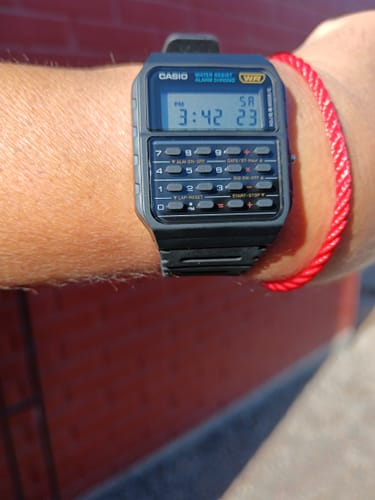 Cliente mostrando su Reloj Calculadora Casio Vintage negro en la muñeca, en un día soleado.