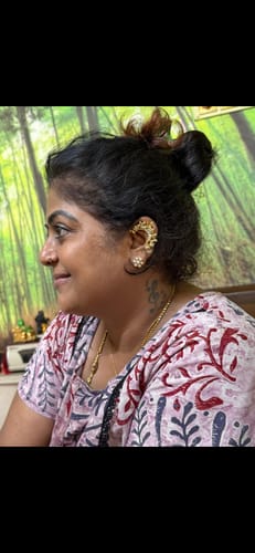 Reviewer shows off the detailed, gold Bala Earcuff worn on their ear.