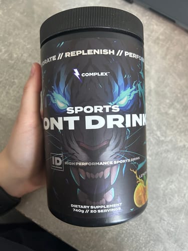 Customer's hand holding a black tub of Complex Sports Ion Drink with a prominent blue tiger graphic on the label.