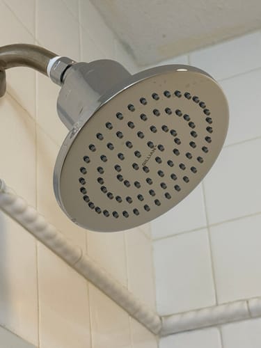 Customer's close-up of the solid metal Gillian Filtered Shower Head installed in a tiled shower.