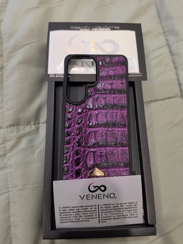 Un cliente muestra su nueva funda S26 Ultra de piel de cocodrilo púrpura en su empaque original.