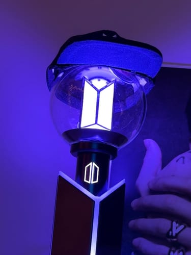 Customer's BTS Official Light Stick Ver.4 illuminated in blue, with a small black accessory on top.