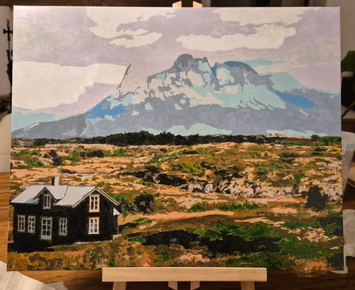 Ein Kunde zeigt sein fertiges Malen-nach-Zahlen-Gemälde einer norwegischen Landschaft mit Haus und Berg.