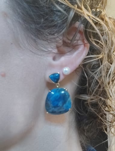 Une cliente portant les boucles d'oreilles pendantes en apatite bleue à son oreille.